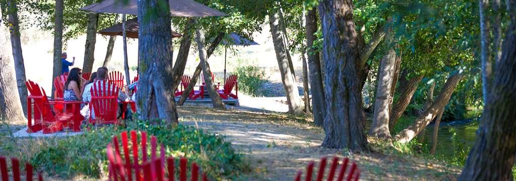 Red Adirondack chairs set up by the Dry Creek ready for tasting.