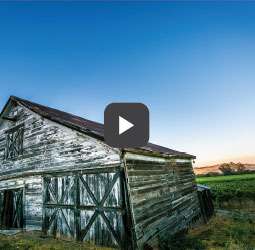 a video clip photo of an old white barn