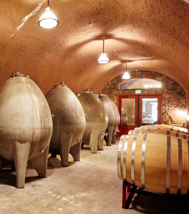 barrels of wine and concrete eggs in a wine cave.