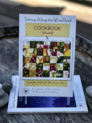 Tasting Along the Wine Road Cookbook volume 5 attractively displayed on a barrel