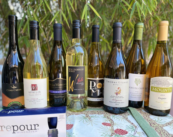 Eight bottles of Viognier from Sonoma County Wineries on a table in front of a tree.