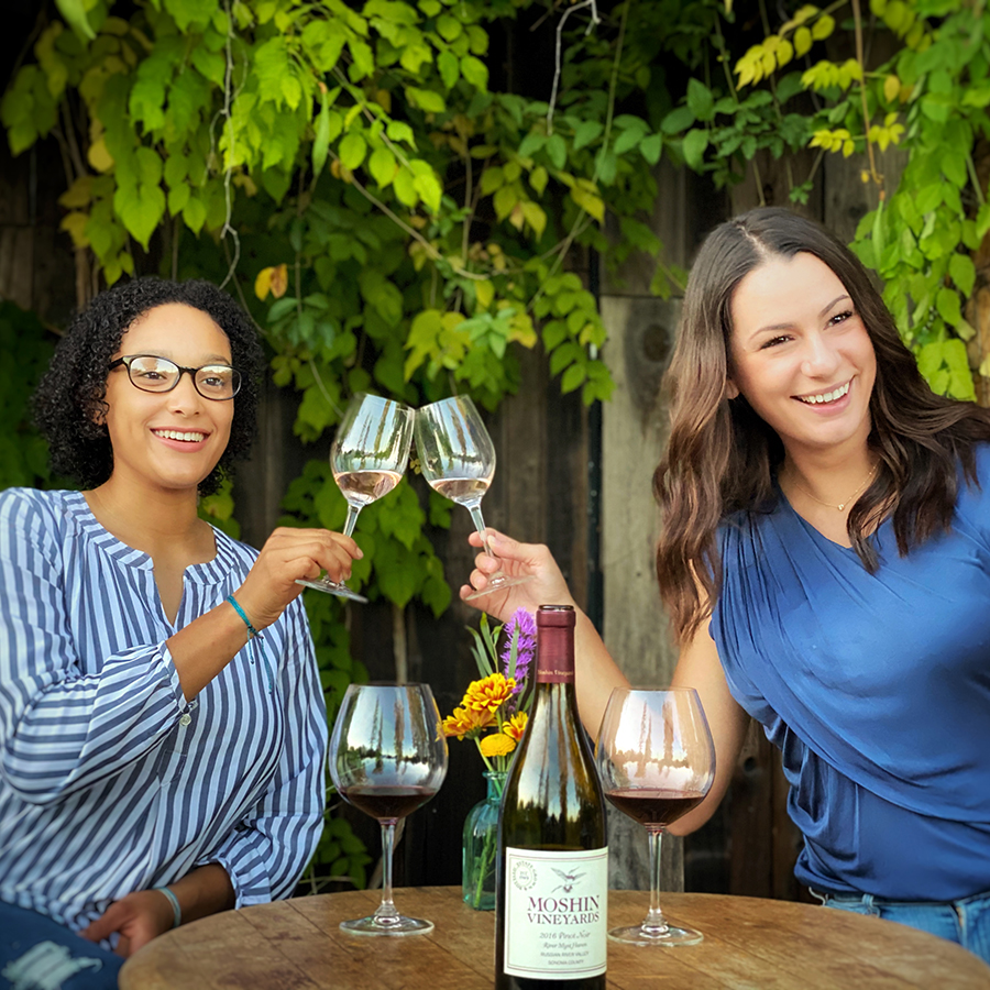Two women toasting two glasses of Moshin Vineyards Pinot Noir.