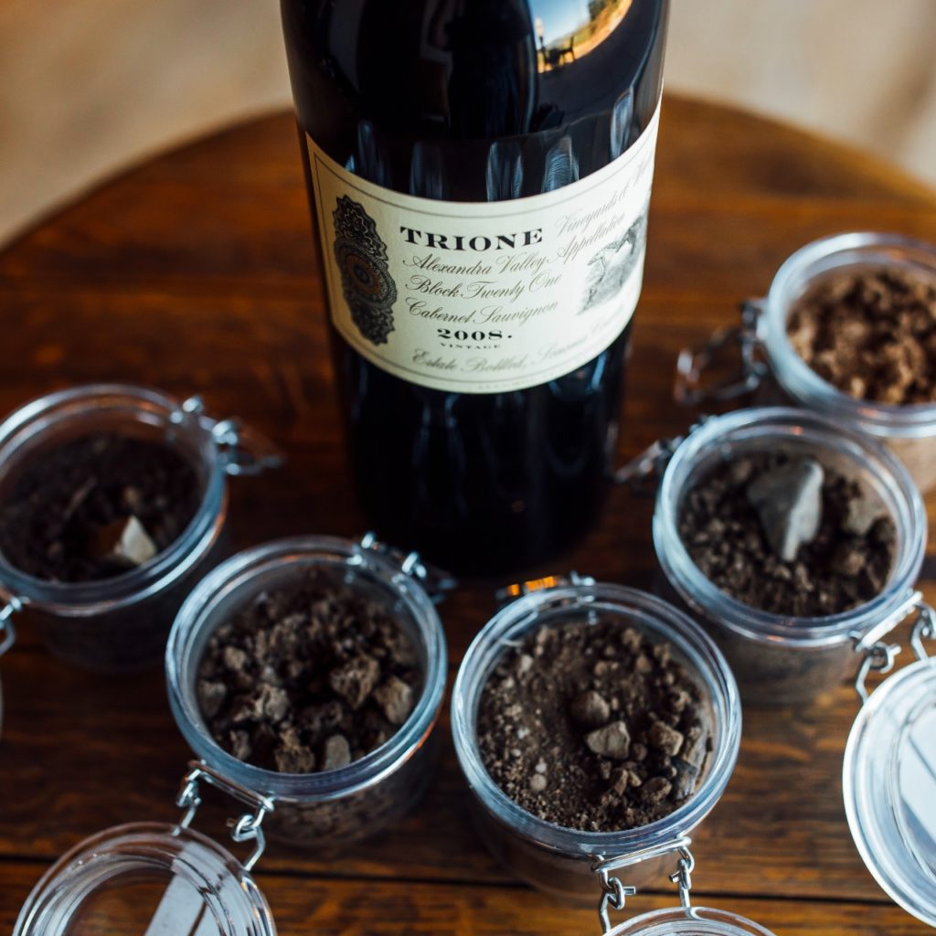 A bottle of Trione Cabernet Sauvignon surrounded by jars of the soil from their five estates.