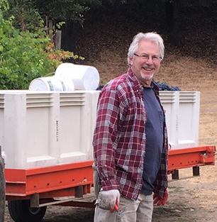 Rick Moshin Winemaker Moshin Vineyards in front of a bin of grapes