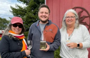 From left to right: Marcy, Glen Kueffner and Beth in front of a red building